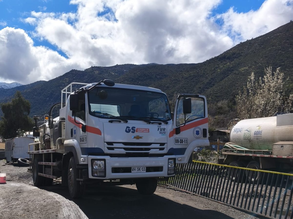 Camión limpiafosas municipal estacionado en el recinto de operaciones, con cerros al fondo.