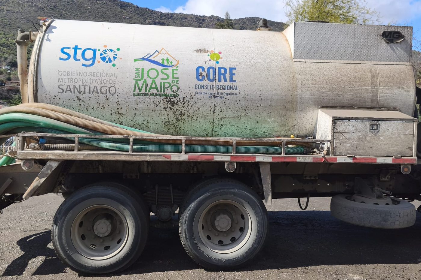 Camión limpiafosas de la Municipalidad de San José de Maipo, visto de costado, con el estanque y las mangueras de succión.